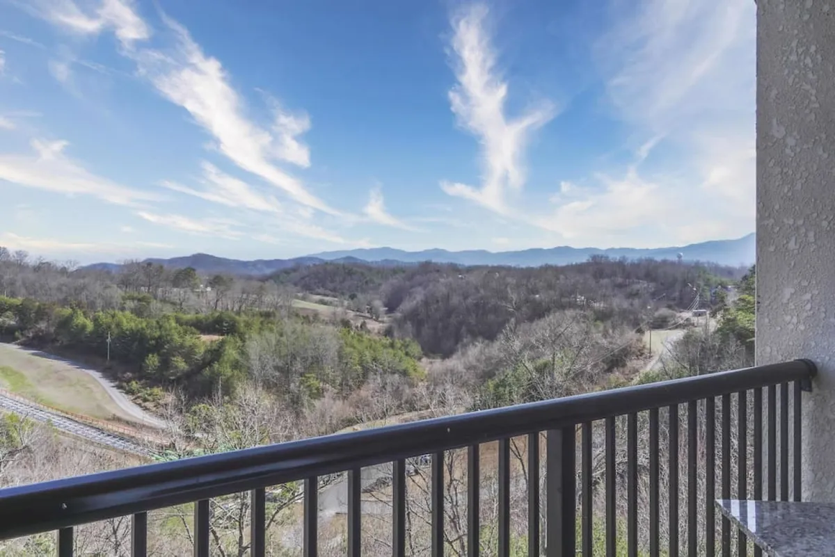A panoramic view of a lush green mountain range under an expansive sky, suggesting the uninterrupted vistas enjoyed from the balcony. The inviting natural landscape evokes a sense of peace and wonder.