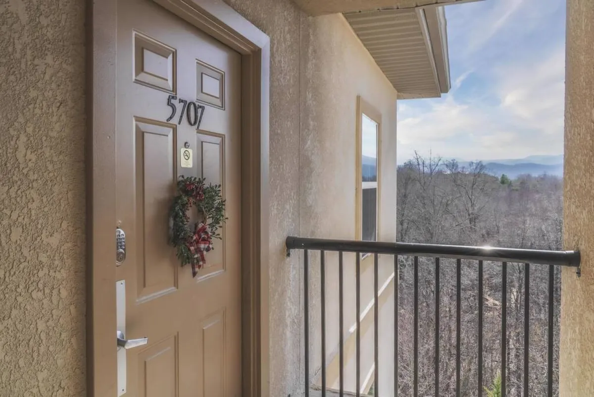 This exterior image captures the welcoming front door of a resort unit, complete with a wreath and a view from the balcony. The scene also hints at the accessibility of the entryway, crucial for guests with mobility needs, and the balcony setting connects guests to the surrounding environment.